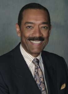 A man in a suit and tie smiling for the camera.